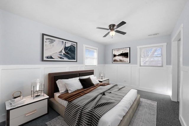 329 Blackhawk Dr, Park Forest, IL 60466 - bedroom featuring wainscoting, a decorative wall, dark carpet, and a ceiling fan