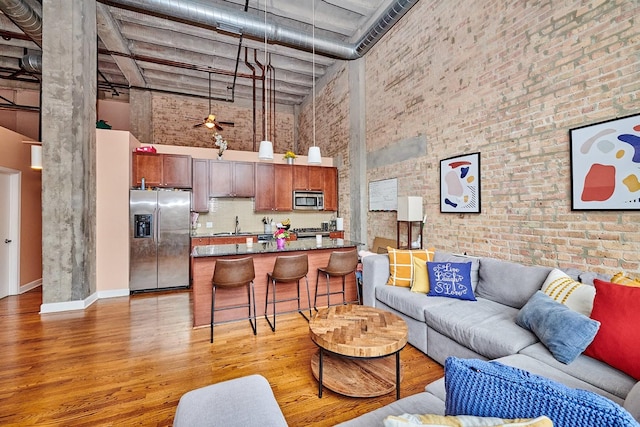 2545 S Dearborn St Unit 323, Chicago, IL 60616 - living room featuring a high ceiling, light wood-style flooring, ceiling fan, and brick wall