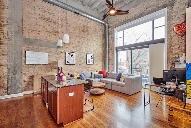 2545 S Dearborn St Unit 323, Chicago, IL 60616 - living room featuring a towering ceiling, brick wall, ceiling fan, and wood finished floors