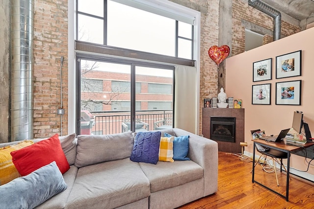 2545 S Dearborn St Unit 323, Chicago, IL 60616 - living room with wood finished floors, a high ceiling, brick wall, and a tile fireplace