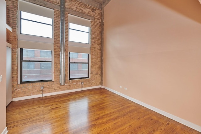 2545 S Dearborn St Unit 323, Chicago, IL 60616 - unfurnished room with wood finished floors, a high ceiling, and brick wall