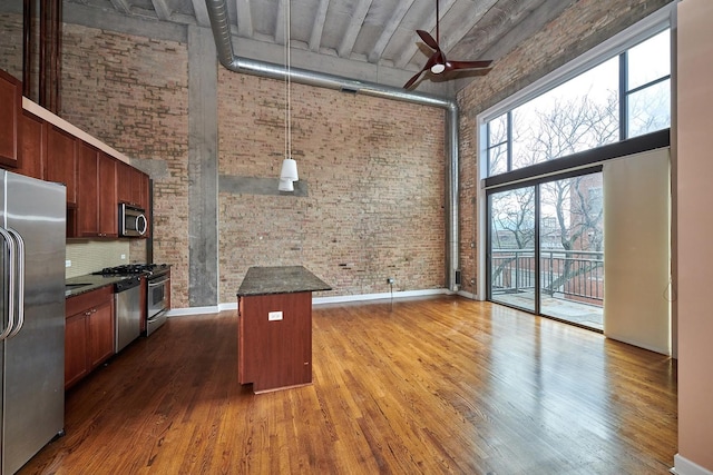 2545 S Dearborn St Unit 323, Chicago, IL 60616 - kitchen with a towering ceiling, stainless steel appliances, brick wall, ceiling fan, and dark wood finished floors