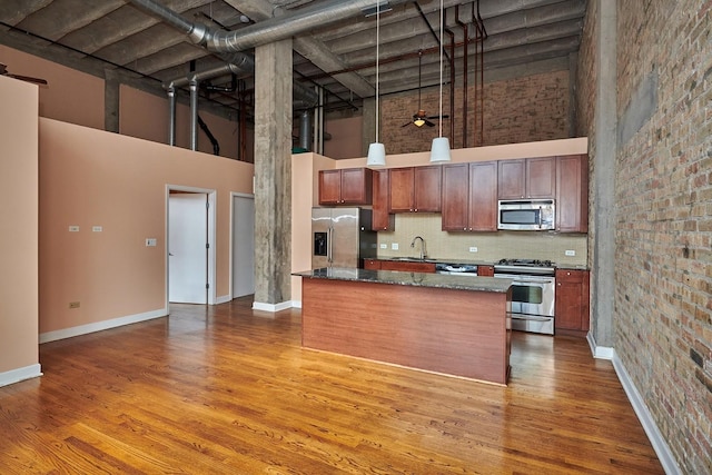 2545 S Dearborn St Unit 323, Chicago, IL 60616 - kitchen with appliances with stainless steel finishes, a towering ceiling, wood finished floors, hanging light fixtures, and decorative backsplash