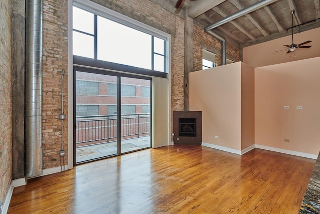2545 S Dearborn St Unit 323, Chicago, IL 60616 - unfurnished living room with a towering ceiling, a ceiling fan, wood finished floors, brick wall, and a tile fireplace