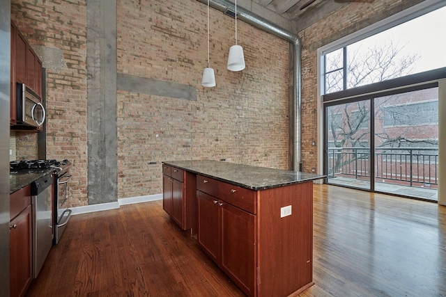 2545 S Dearborn St Unit 323, Chicago, IL 60616 - kitchen featuring stainless steel microwave, brick wall, a high ceiling, dark wood-style floors, and dark stone countertops