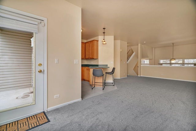 1109 Longwood Dr, Lisle, IL 60532 - kitchen featuring a breakfast bar area, light colored carpet, dark countertops, pendant lighting, and light tile patterned floors
