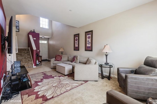 carpeted living area featuring stairway and baseboards