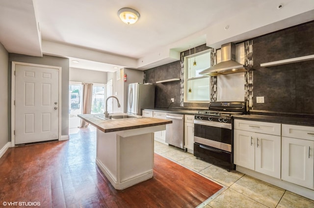 2939 N Springfield Ave, Chicago, IL 60618 - kitchen featuring wall chimney exhaust hood, stainless steel appliances, decorative backsplash, a kitchen island with sink, and white cabinets