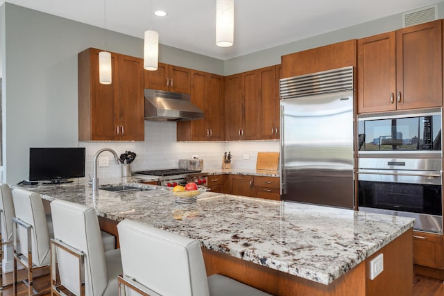 540 W Webster Ave Unit 611, Chicago, IL 60614 - kitchen featuring under cabinet range hood, built in appliances, a peninsula, light stone counters, and tasteful backsplash