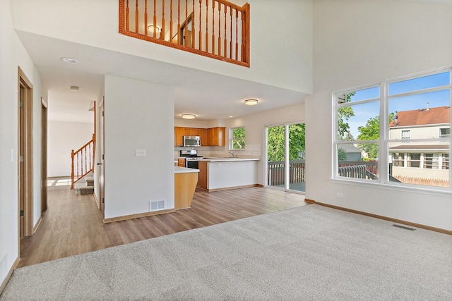 2315 Woodside Dr, Carpentersville, IL 60110 - unfurnished living room featuring stairway, light carpet, light wood-style flooring, and a towering ceiling