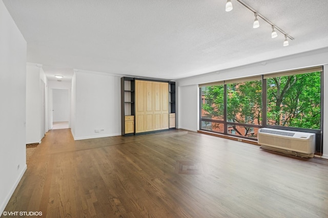 1169 S Plymouth Ct Unit 406, Chicago, IL 60605 - unfurnished room featuring an AC wall unit, rail lighting, a textured ceiling, and wood finished floors