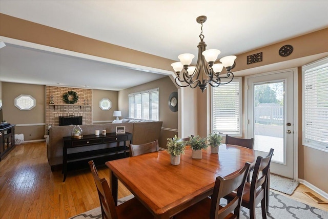 13907 W Big Run Ln, Homer Glen, IL 60491 - dining space featuring light wood-type flooring, a chandelier, and a fireplace