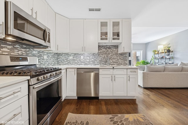 5862 N Lincoln Ave Unit 3A, Chicago, IL 60659 - kitchen featuring appliances with stainless steel finishes, light countertops, tasteful backsplash, dark wood-style floors, and glass insert cabinets