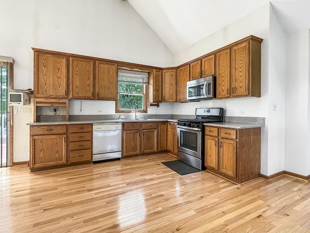 1905 E Grand Ave, Lindenhurst, IL 60046 - kitchen with appliances with stainless steel finishes, high vaulted ceiling, brown cabinetry, and light wood finished floors