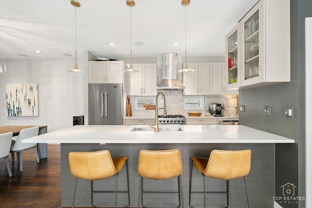 3800 N Christiana Ave, Chicago, IL 60618 - kitchen featuring wall chimney exhaust hood, high quality fridge, glass insert cabinets, a breakfast bar, and wallpapered walls