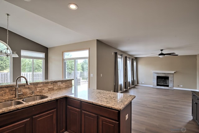 2141 Bluemist Dr, Aurora, IL 60504 - kitchen featuring ceiling fan, wood finished floors, a glass covered fireplace, light stone countertops, and vaulted ceiling
