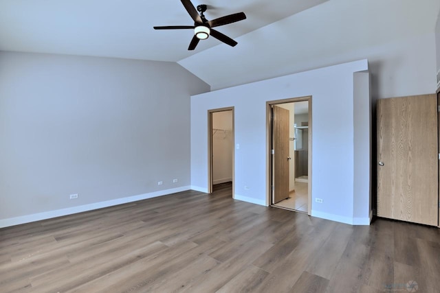 2141 Bluemist Dr, Aurora, IL 60504 - unfurnished bedroom featuring a walk in closet, vaulted ceiling, wood finished floors, connected bathroom, and ceiling fan
