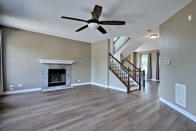2141 Bluemist Dr, Aurora, IL 60504 - unfurnished living room with wood finished floors, stairs, a ceiling fan, and a tiled fireplace