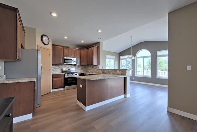 2141 Bluemist Dr, Aurora, IL 60504 - kitchen featuring appliances with stainless steel finishes, a peninsula, light wood-type flooring, backsplash, and lofted ceiling