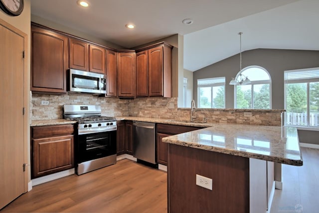 2141 Bluemist Dr, Aurora, IL 60504 - kitchen with stainless steel appliances, a peninsula, light wood-type flooring, lofted ceiling, and light stone countertops