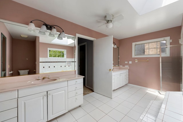 201 E White Oak St, Arlington Heights, IL 60005 - bathroom featuring tile patterned flooring, two vanities, a ceiling fan, a walk in shower, and a skylight