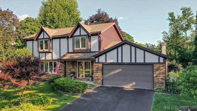 1054 Maple Ln, Batavia, IL 60510 - tudor house with asphalt driveway, brick siding, a garage, a front lawn, and a shingled roof