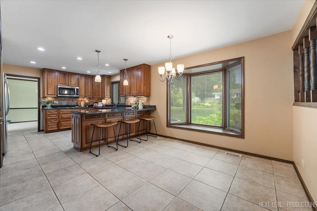 1054 Maple Ln, Batavia, IL 60510 - kitchen with stainless steel microwave, brown cabinets, dark countertops, decorative backsplash, and recessed lighting