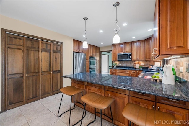 1054 Maple Ln, Batavia, IL 60510 - kitchen featuring appliances with stainless steel finishes, brown cabinets, decorative backsplash, a peninsula, and light tile patterned floors