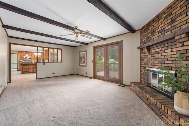 1054 Maple Ln, Batavia, IL 60510 - unfurnished living room featuring beam ceiling, light colored carpet, a ceiling fan, a brick fireplace, and french doors