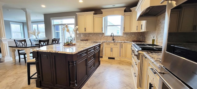 3004 Wayland Ave, Elgin, IL 60124 - kitchen featuring under cabinet range hood, cream cabinets, ornate columns, plenty of natural light, and recessed lighting