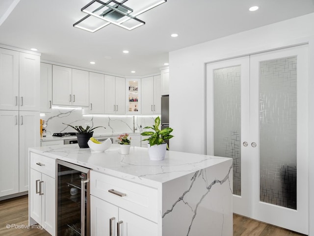 400 E Randolph St Unit 3225, Chicago, IL 60601 - kitchen with beverage cooler, light wood finished floors, white cabinets, glass insert cabinets, and a center island