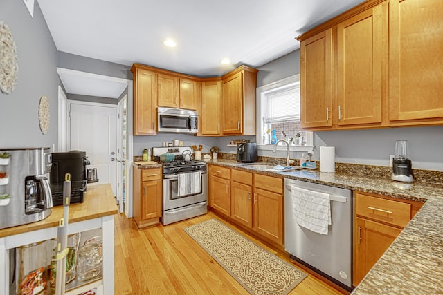 4825 N Karlov Ave, Chicago, IL 60630 - kitchen featuring stainless steel appliances, light wood-style flooring, dark stone counters, recessed lighting, and brown cabinets