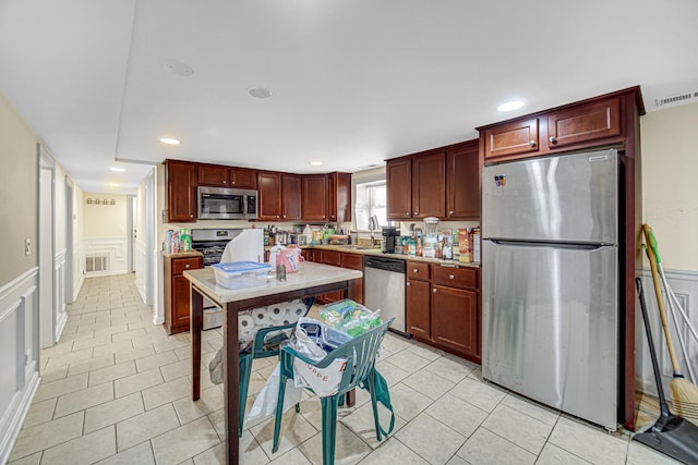4825 N Karlov Ave, Chicago, IL 60630 - kitchen with appliances with stainless steel finishes, a decorative wall, dark brown cabinets, light tile patterned floors, and a wainscoted wall