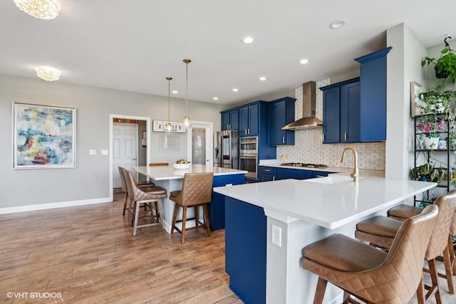 26930 Thornwood Blvd, Plainfield, IL 60585 - kitchen with wall chimney range hood, blue cabinets, a breakfast bar area, appliances with stainless steel finishes, and tasteful backsplash