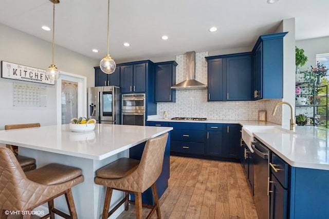 26930 Thornwood Blvd, Plainfield, IL 60585 - kitchen featuring wall chimney range hood, stainless steel appliances, blue cabinetry, a kitchen bar, and recessed lighting