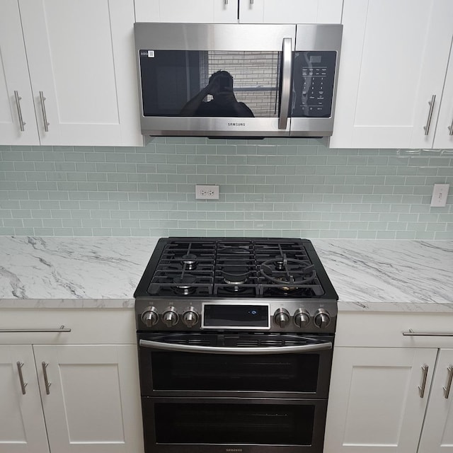 5823 W Addison St, Chicago, IL 60634 - kitchen featuring stainless steel appliances, white cabinets, decorative backsplash, and light stone counters