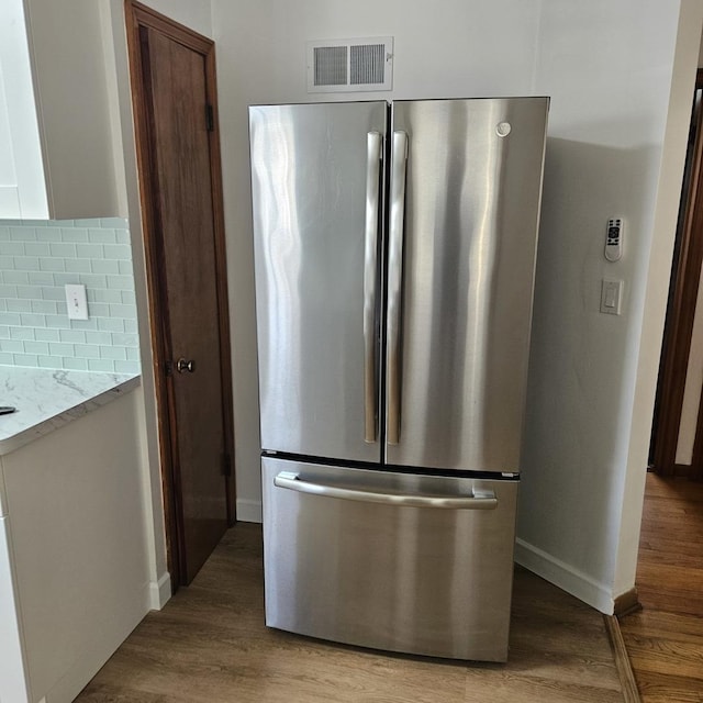 5823 W Addison St, Chicago, IL 60634 - kitchen featuring freestanding refrigerator, decorative backsplash, light wood-style flooring, and light stone counters