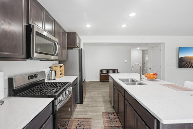 1917 Turtle Creek Ct, Aurora, IL 60503 - kitchen with appliances with stainless steel finishes, an island with sink, dark brown cabinets, light wood-style flooring, and light countertops