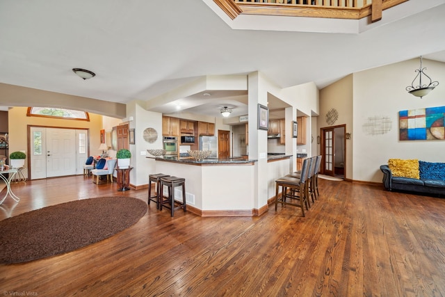 26200 W Chatham Dr, Plainfield, IL 60585 - kitchen featuring stainless steel appliances, dark countertops, dark wood-type flooring, a kitchen bar, and brown cabinets