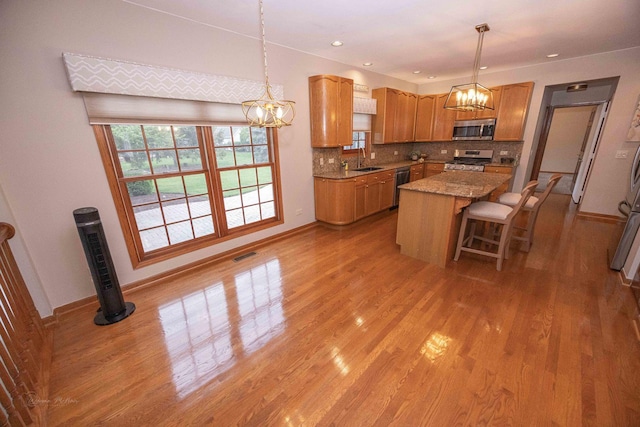 14803 S Hawthorn Cir, Plainfield, IL 60544 - kitchen with stainless steel appliances, a chandelier, a center island, tasteful backsplash, and light wood-type flooring