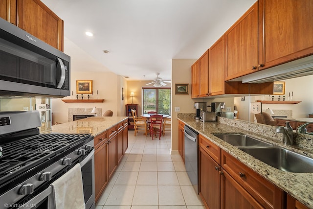 865 E 22nd St Unit 214, Lombard, IL 60148 - kitchen with stainless steel appliances, a fireplace, a ceiling fan, light tile patterned floors, and brown cabinetry
