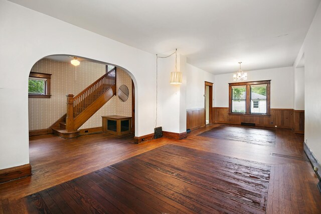 866 S Evergreen Ave, Kankakee, IL 60901 - unfurnished living room with hardwood / wood-style flooring, arched walkways, stairs, a wainscoted wall, and a chandelier