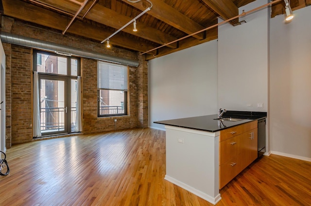 1040 W Adams St Unit 257, Chicago, IL 60607 - kitchen with brick wall, rail lighting, light wood-style floors, dark countertops, and plenty of natural light