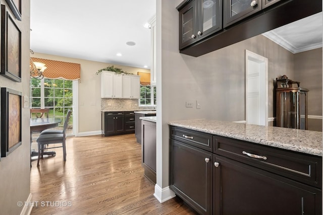 605 Red Cypress Dr, Cary, IL 60013 - kitchen featuring light wood-style floors, white cabinets, glass insert cabinets, a chandelier, and light stone counters