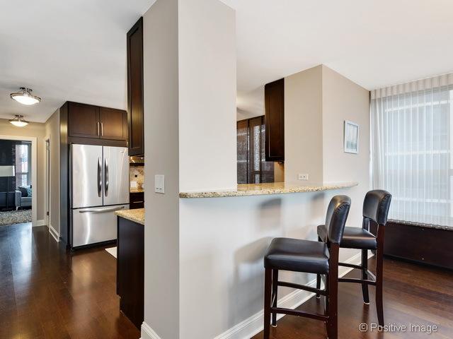 1550 N Lake Shore Dr Unit 3G, Chicago, IL 60610 - kitchen featuring freestanding refrigerator, dark wood finished floors, a breakfast bar, and dark brown cabinetry