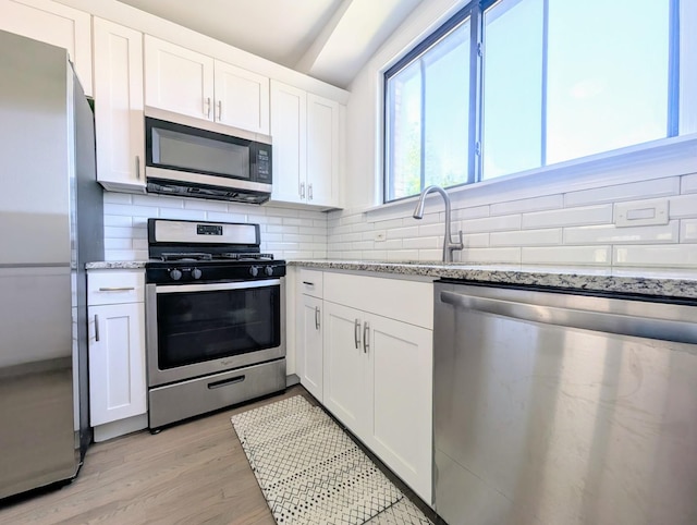 5655 N Spaulding Ave Unit 2W, Chicago, IL 60659 - kitchen featuring stainless steel appliances, decorative backsplash, white cabinetry, and light stone counters