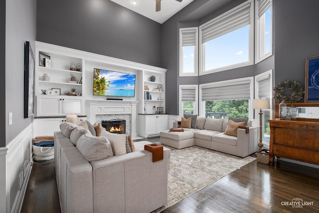 40W379 E Laura Ingalls Wilder Rd, Saint Charles, IL 60175 - living area with a high ceiling, a lit fireplace, wood finished floors, ceiling fan, and wainscoting