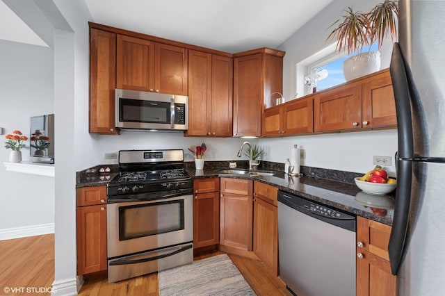 2709 W Belden Ave Unit 3, Chicago, IL 60647 - kitchen with appliances with stainless steel finishes, light wood-style flooring, dark stone counters, and brown cabinetry