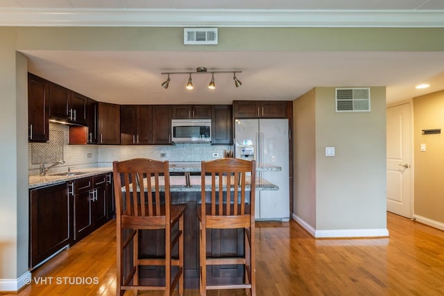 100 Deborah Ln Unit B23, Wheeling, IL 60090 - kitchen featuring white refrigerator with ice dispenser, stainless steel microwave, dark brown cabinets, tasteful backsplash, and light wood finished floors