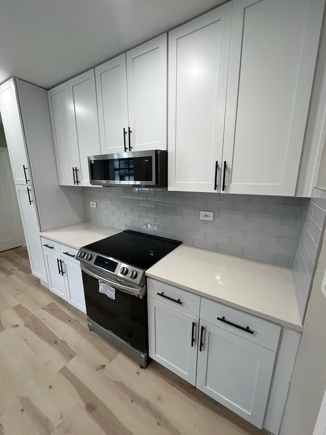 4021 W Estes Ave, Lincolnwood, IL 60712 - kitchen with stainless steel appliances, light wood-type flooring, white cabinetry, and light stone countertops